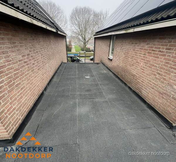 Plat dak met bitumen dakbedekking tussen bakstenen muren in Nootdorp Plat dak met bitumen dakbedekking tussen bakstenen muren in Nootdorp