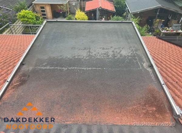 Verouderd plat dak met slijtage tussen schuine daken in Nootdorp Verouderd plat dak met slijtage tussen schuine daken in Nootdorp